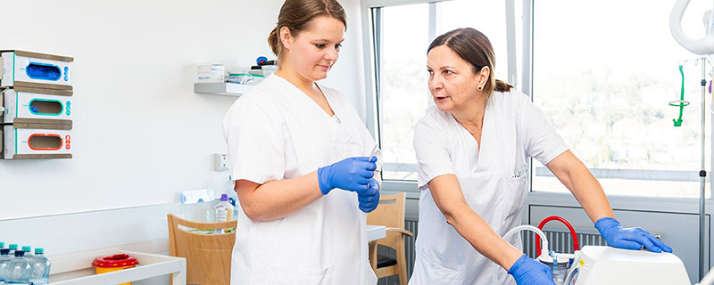 Fünf Pflegekräfte in Arbeitskleidung lächeln